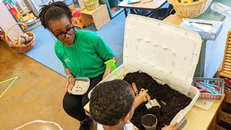 Chastity Bey helps a child plant seeds during a school program