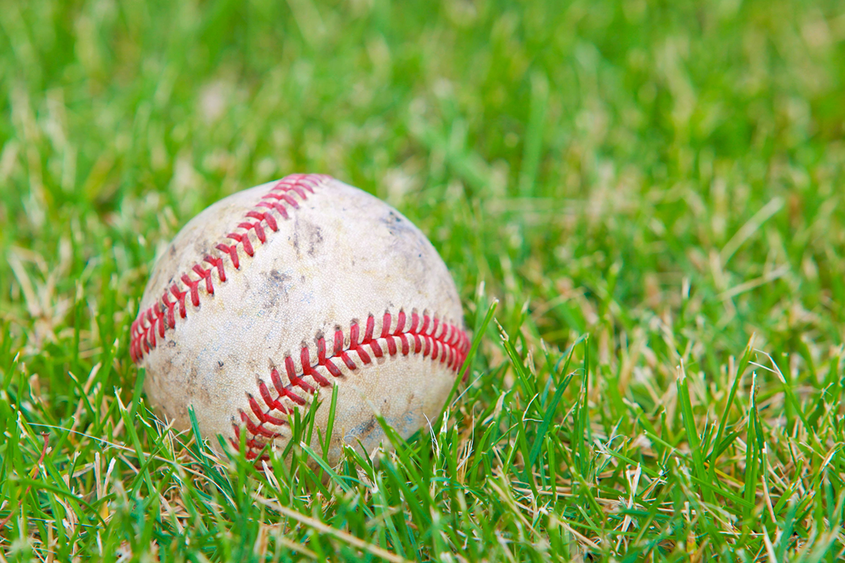 A baseball sitting in a field of grass